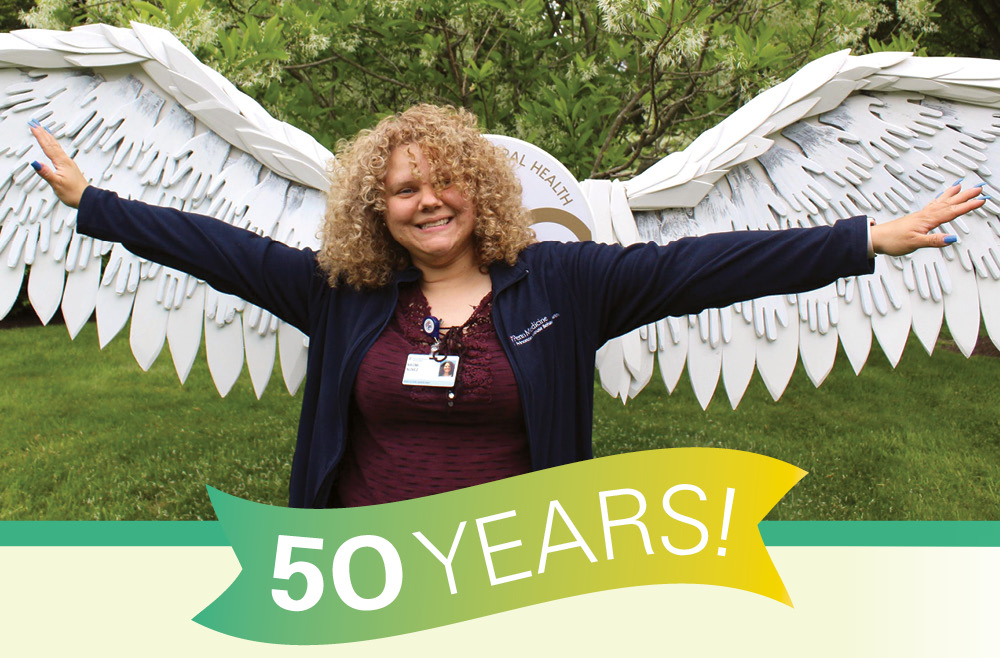 Naomi Nunez, an employee of Princeton House Behavioral Health, standing in front of angel wings